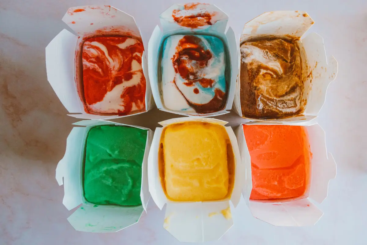 Six open takeout boxes, seen from above, each packed with a different flavor of ice cream.