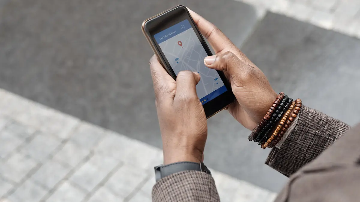 Two hands hold a phone that shows a street map with a red pin.